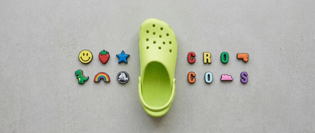 Output: the empty clog in the center with every charm arranged in a grid around it, shot from above